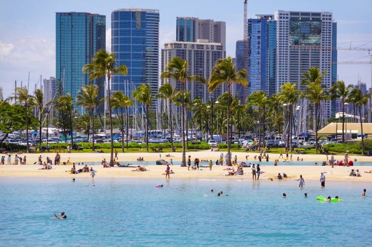 people in water at Waikiki Beach with buildings in background